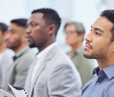 Business man audience and listening to seminar presentation and salesman at team training workshop Meeting group and serious professional at conference with crowd at convention event for speech