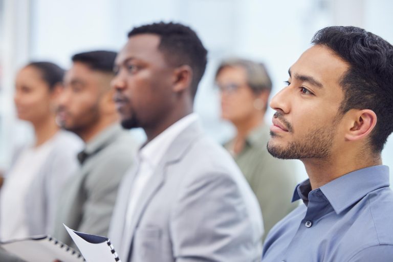 Business man audience and listening to seminar presentation and salesman at team training workshop Meeting group and serious professional at conference with crowd at convention event for speech